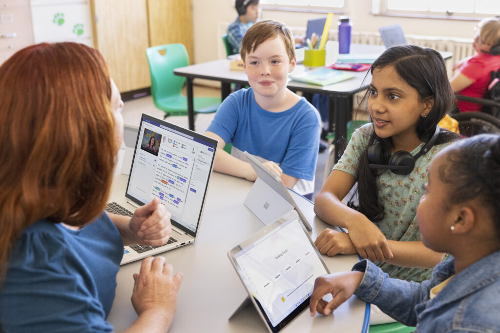 Teacher and students at a classroom table.